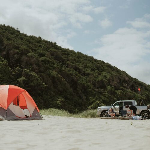 Pick-up posé sur le sable à côté d'une tente de camping