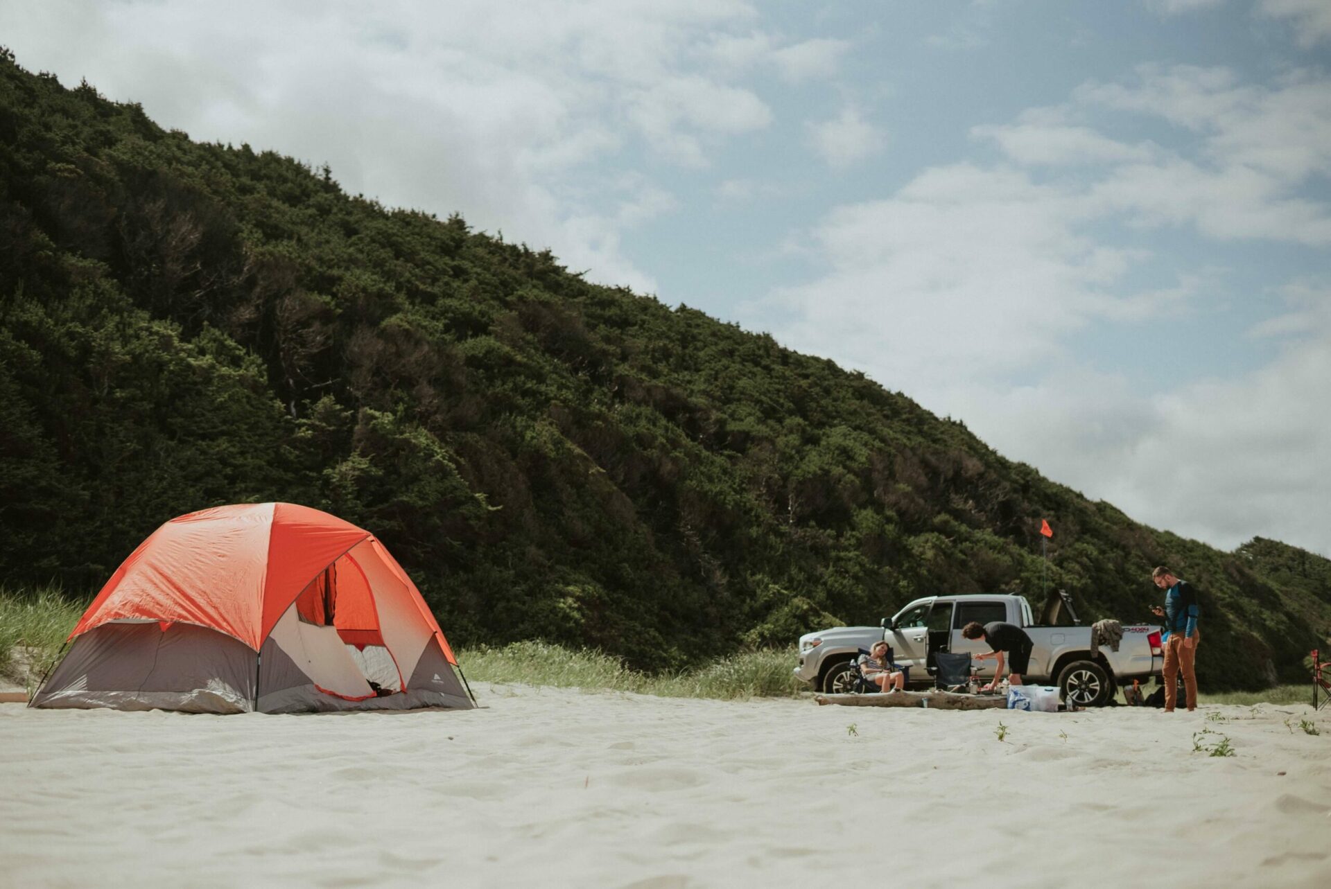 Pick-up posé sur le sable à côté d'une tente de camping